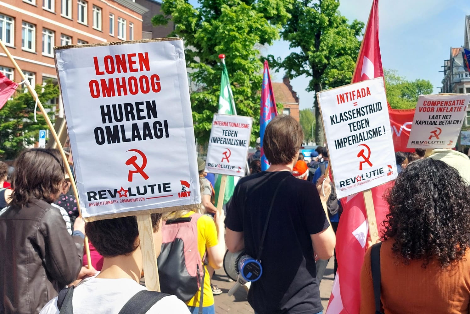 Demonstrant van Revolutie met bord dat zegt "Lonen omhoog, huren omlaag"